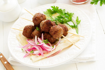 Lamb kebabs on skewers with onion and buttermilk sauce.