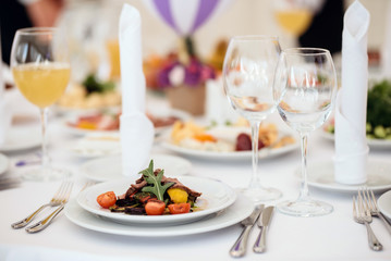 Tasty steak with fried vegetables on table in restaurant on wedding party