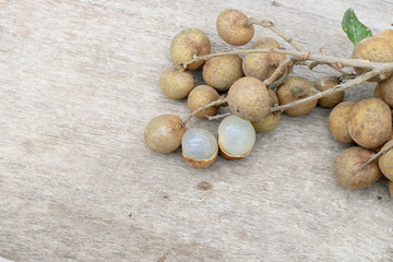 Longan Fresh. A bunch of Longan and Peel on a wooden background with green natural background in the garden from northen Thailand.  sweet and fragrant,The brown fruit looks like a sphere.