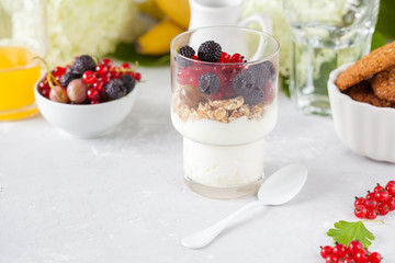 Healthy light breakfast: parfait with berries and yogurt, orange juice and biscuits.