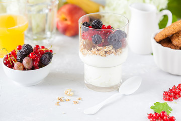 Healthy light breakfast: parfait with berries and yogurt, orange juice and biscuits.