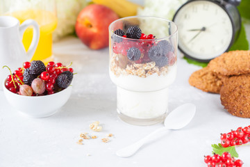 Healthy light breakfast: parfait with berries and yogurt, orange juice and biscuits.