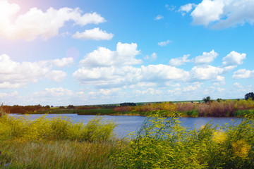 Beautiful clouds on a blue sky over a summer meadow and a small river