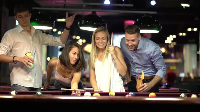 four young women and men playing billiard together
