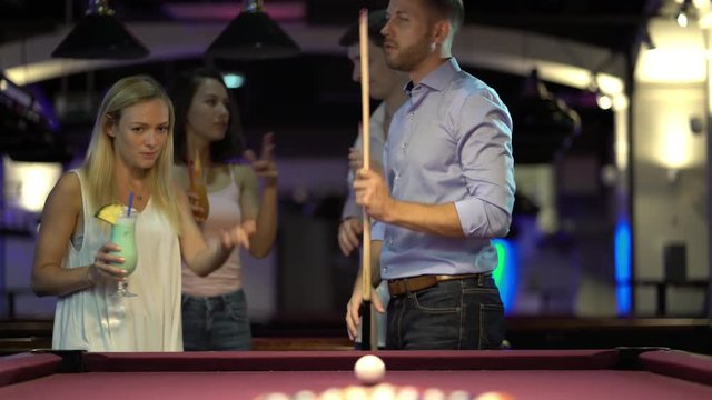 4k video two young couples playing billiard together, man starting game
