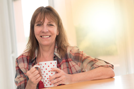 Portrait of mature woman smiling and holding a mug, light effect
