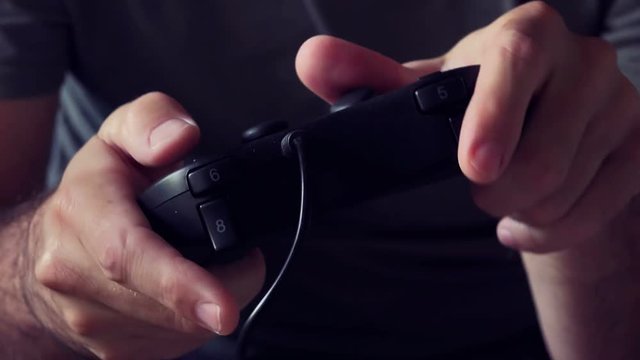 Close up of male hands with game controller playing video games, entertainment technology and lifestyle