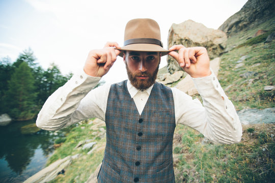 Hipster handsome male model portrait with beard wearing trendy clothes in the mountains