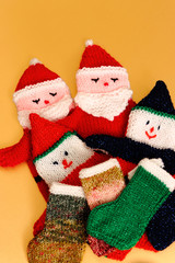 Knitted Father Christmas glove puppets and stockings on a gold background