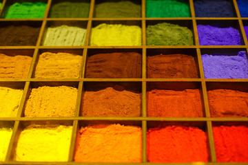 Colorful powder in wooden boxes on the display case