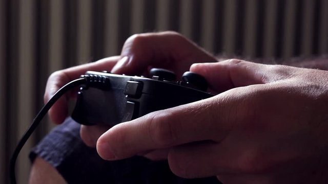 Close up of male hands with game controller playing video games, entertainment technology and lifestyle