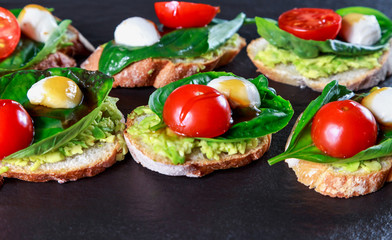 tapas with avocado, boiled quail eggs and Basil with teriyaki sauce on a black granite surface table
