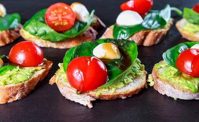 tapas with avocado, boiled quail eggs and Basil with teriyaki sauce on a black granite surface table