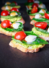 tapas with avocado, boiled quail eggs and Basil with teriyaki sauce on a black granite surface table