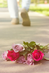 rose bouquet left on ground men feet leaving on a background