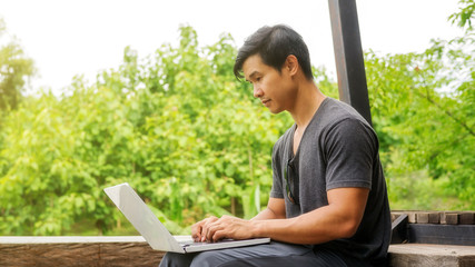 Asian man using a laptop on the balcony.