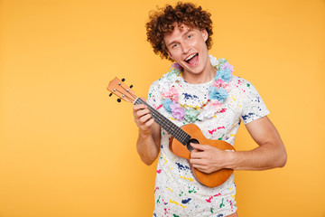 Attractive young man in summer clothes playing ukulele