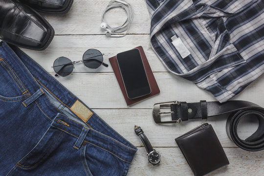 Top view / Flat lay accessory to travel with man / gentlemen clothing concept.Items the shirt jean and mobile phone on rustic white wooden background.watch,sunglasses and shoes on wood table .