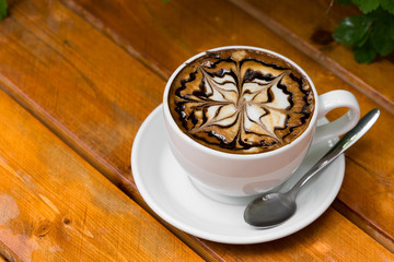 Coffee cup of cappuccino. Hot Cappuccino coffee with zigzag caramel on wooden background.
