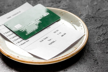 restaurant bill on plate paying by credit card on dark table background