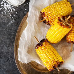 Corn grilled with salt and spices. Dark background. Fast food in