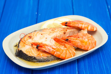 fried salmon with shrimps on white dish on wooden background
