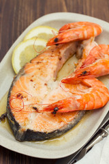 fried salmon with shrimps on white dish on wooden background