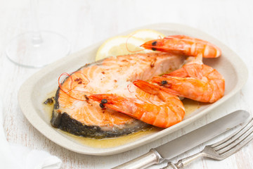 fried salmon with shrimps on white dish on wooden background