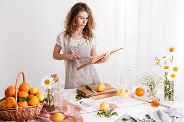 Woman standing indoors near table with a lot of citruses