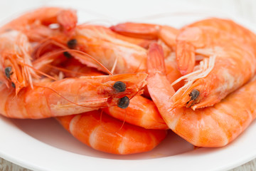 boiled shrimps on white dish on wooden background