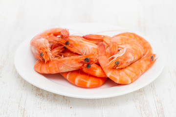 boiled shrimps on white dish on wooden background
