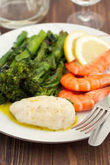 boiled fish with greens and shrimps on white dish