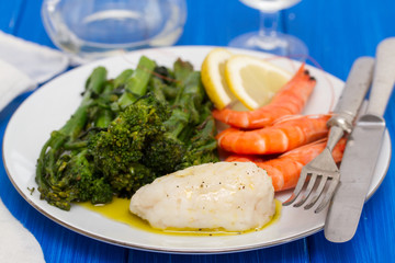 boiled fish with greens and shrimps on white dish