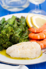boiled fish with greens and shrimps on white dish