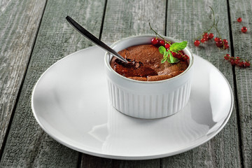 Chocolate mousse for the dessert course on a plate. Tasty chocolate dessert on a wooden table. Close-up shot.