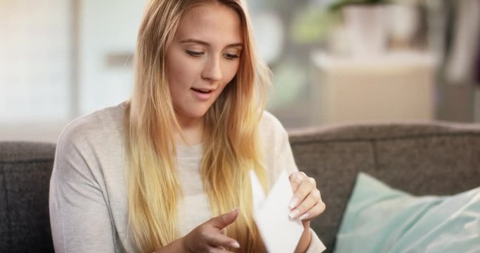 Beautiful young woman opening envelope and reading a love letter