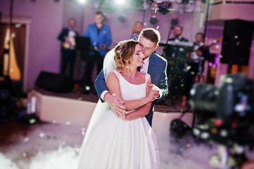 Newly married couple dancing on their wedding party with heavy smoke and multicolored lights on the...