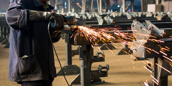Worker grinding metal with angle grinder