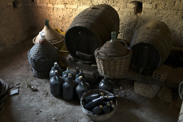 old demijohns aged wine bottles and wooden barrels in a basement