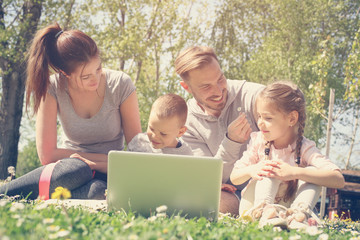 Family using laptop on the meadow.