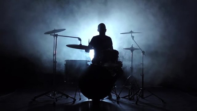 Energetic music in the performance of a professional drummer. Black background. Silhouette. Slow motion