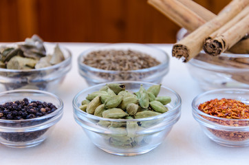 Different kind of indian spices such as cardamom, cumin, curry leaves,  cinnamon in glass bowls. 