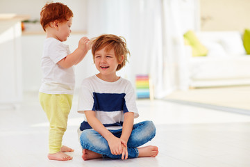 young kid tolerating a junior brother game with his hair