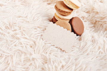 Macarons with paper blank copy space. Macarons of coffee color on a soft background, with a blank for a design.