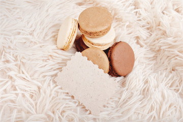 Macarons with paper blank copy space. Macarons of coffee color on a soft background, with a blank for a design.