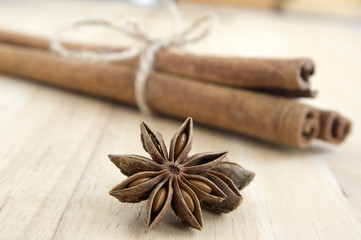 Fresh raw cinnamon sticks tied with natural twine and star anise on wooden table