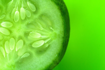 a slice of cucumber on a green background. copy space for skin care products  or a refreshing drink with cucumber