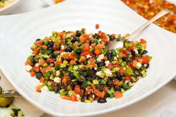 Salad from finely chopped cucumbers, tomatoes, greens and black olives
