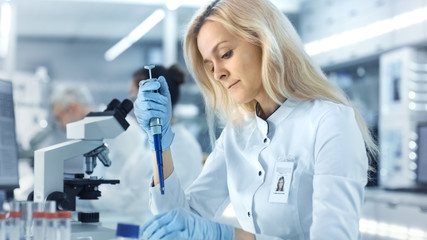 Female Research Scientist Uses Micropipette Filling Test Tubes. Scientist Work in a Big Laboratory/ Research Center.