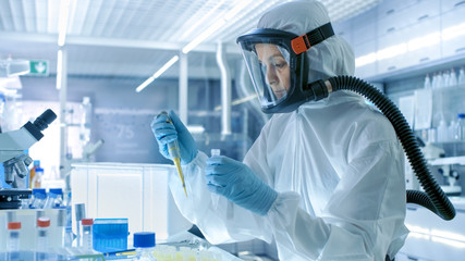 Medical Virology Research Scientist Works in a Hazmat Suit with Mask, She Uses Micropipette. She...